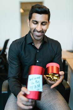 Smiling man in office holding a welcome gift box with a note.