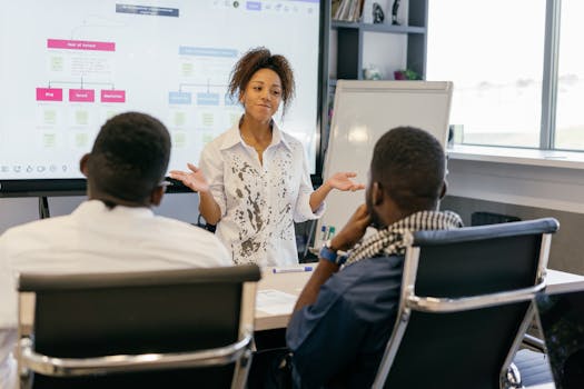 A woman leads a team meeting in a modern office using digital presentations.