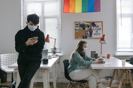 Team members in masks collaborate in a modern office with a focus on safety.